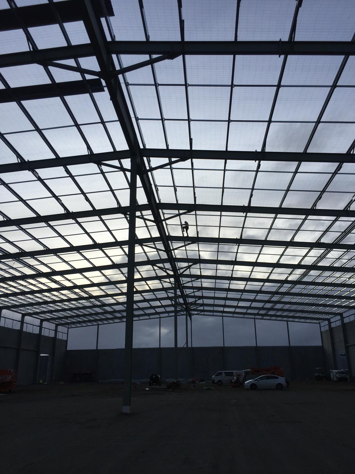 Interior of a large warehouse steel frame with crew and elevated work platforms