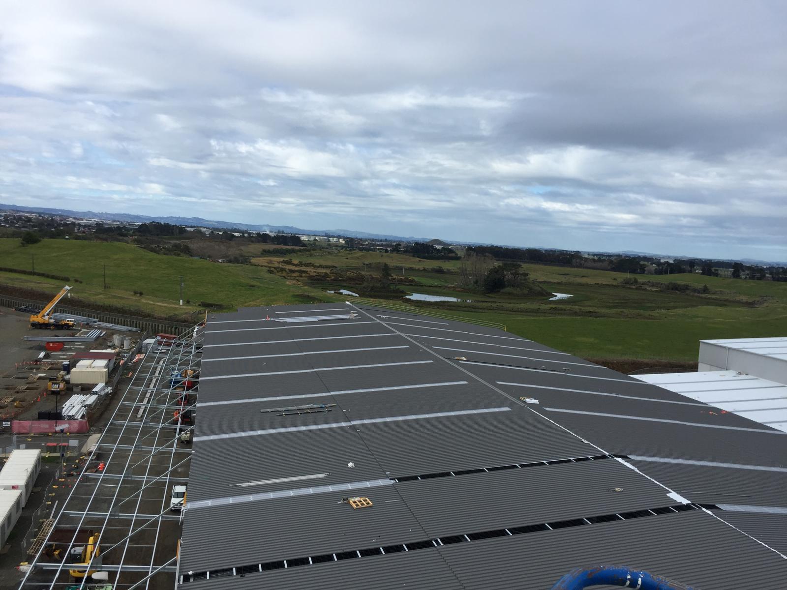 Aerial view of a large grey long-run commercial roof