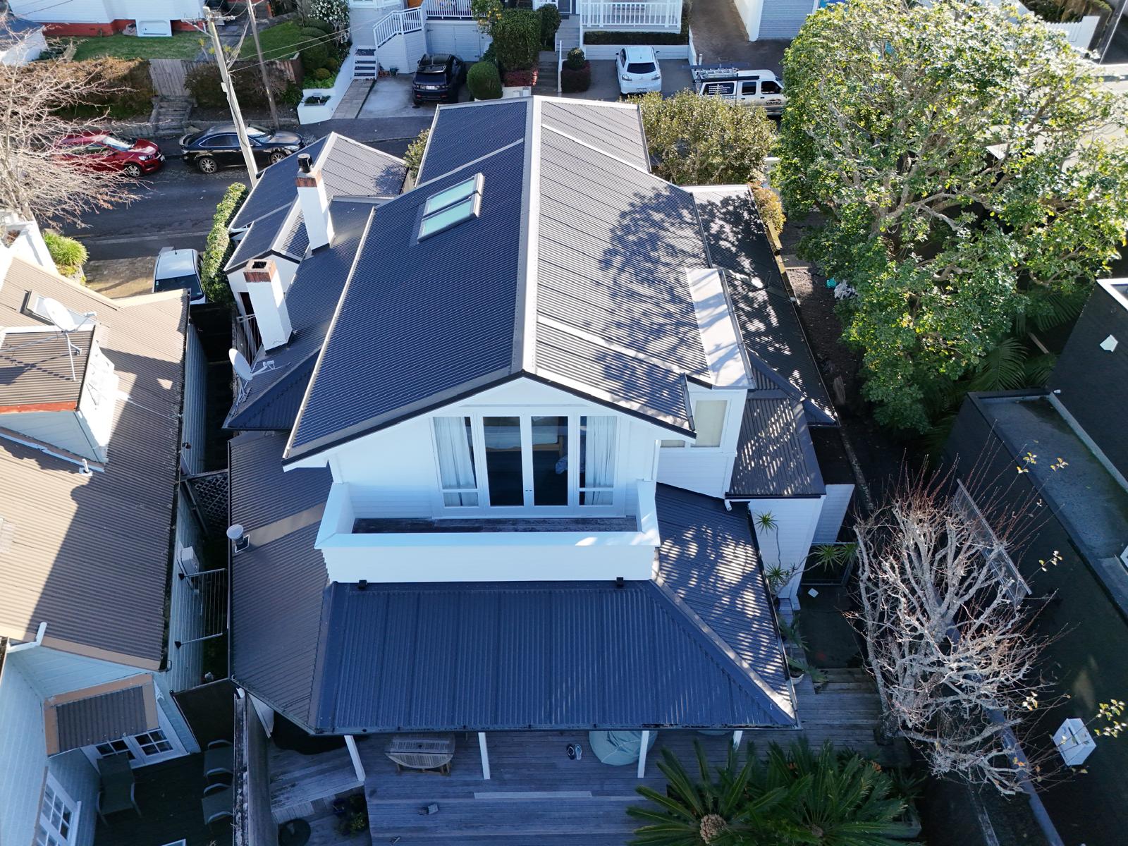 Aerial view of a completed dark long-run roof on a character villa