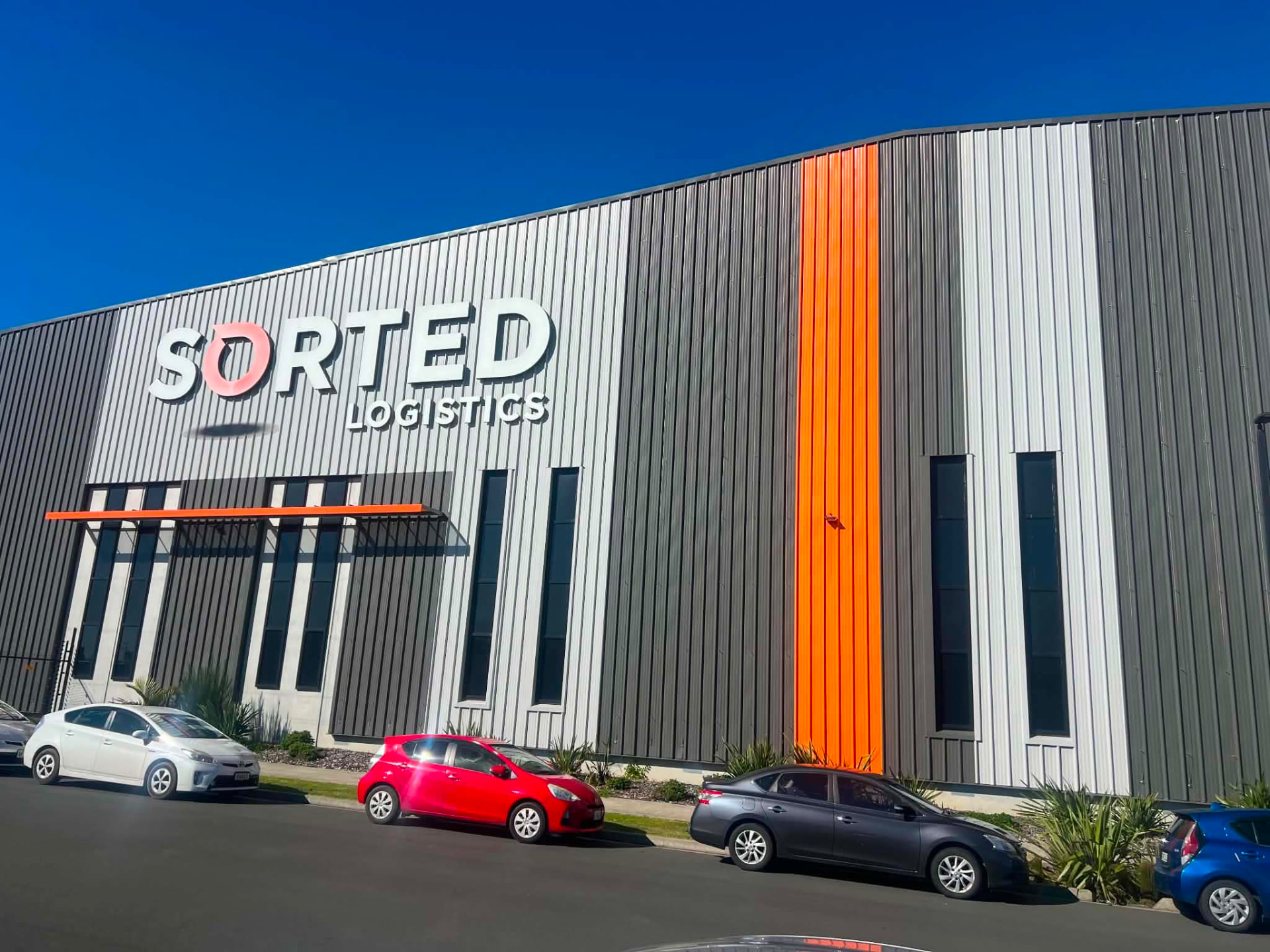 Commercial building with long-run steel wall cladding and orange feature detail