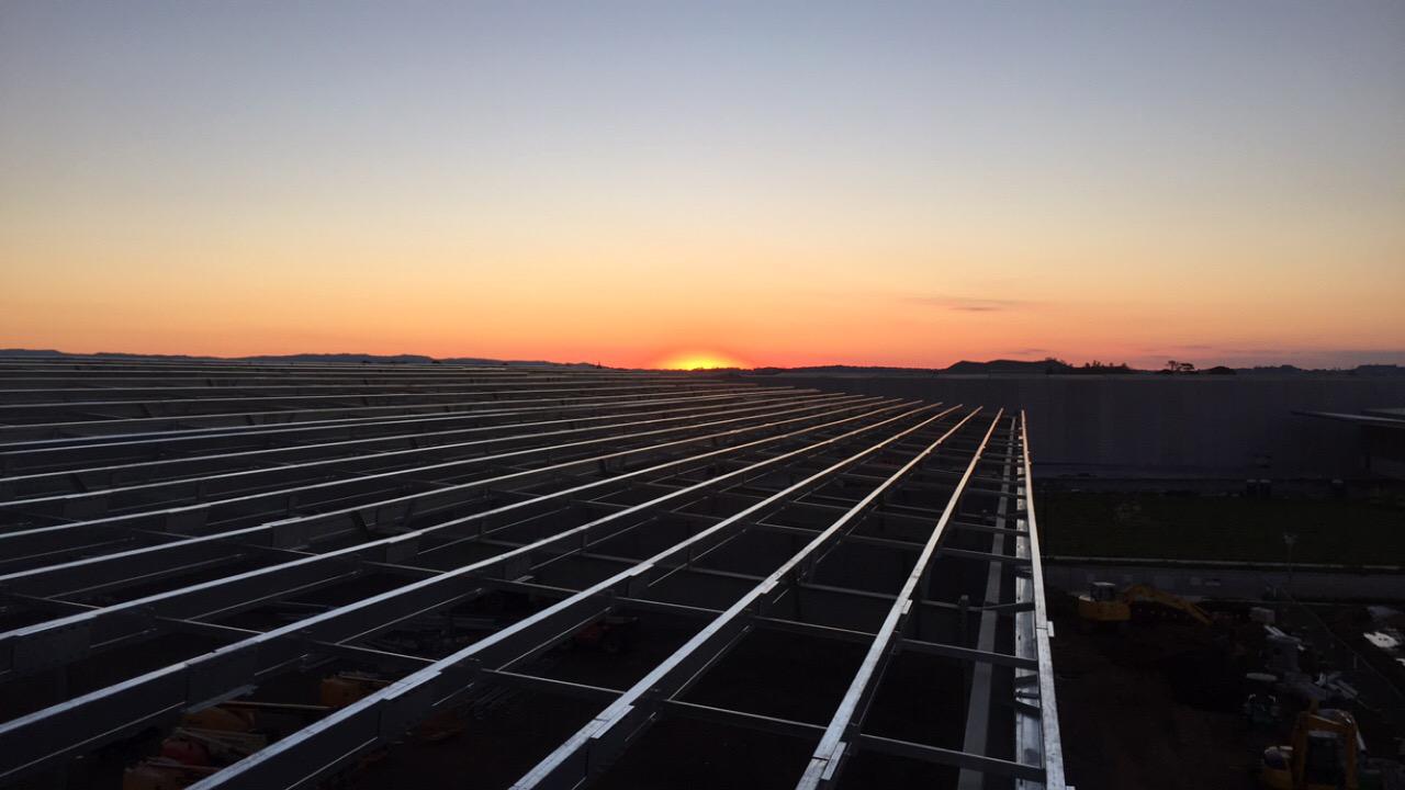 Purlins running across a commercial roof frame at sunset