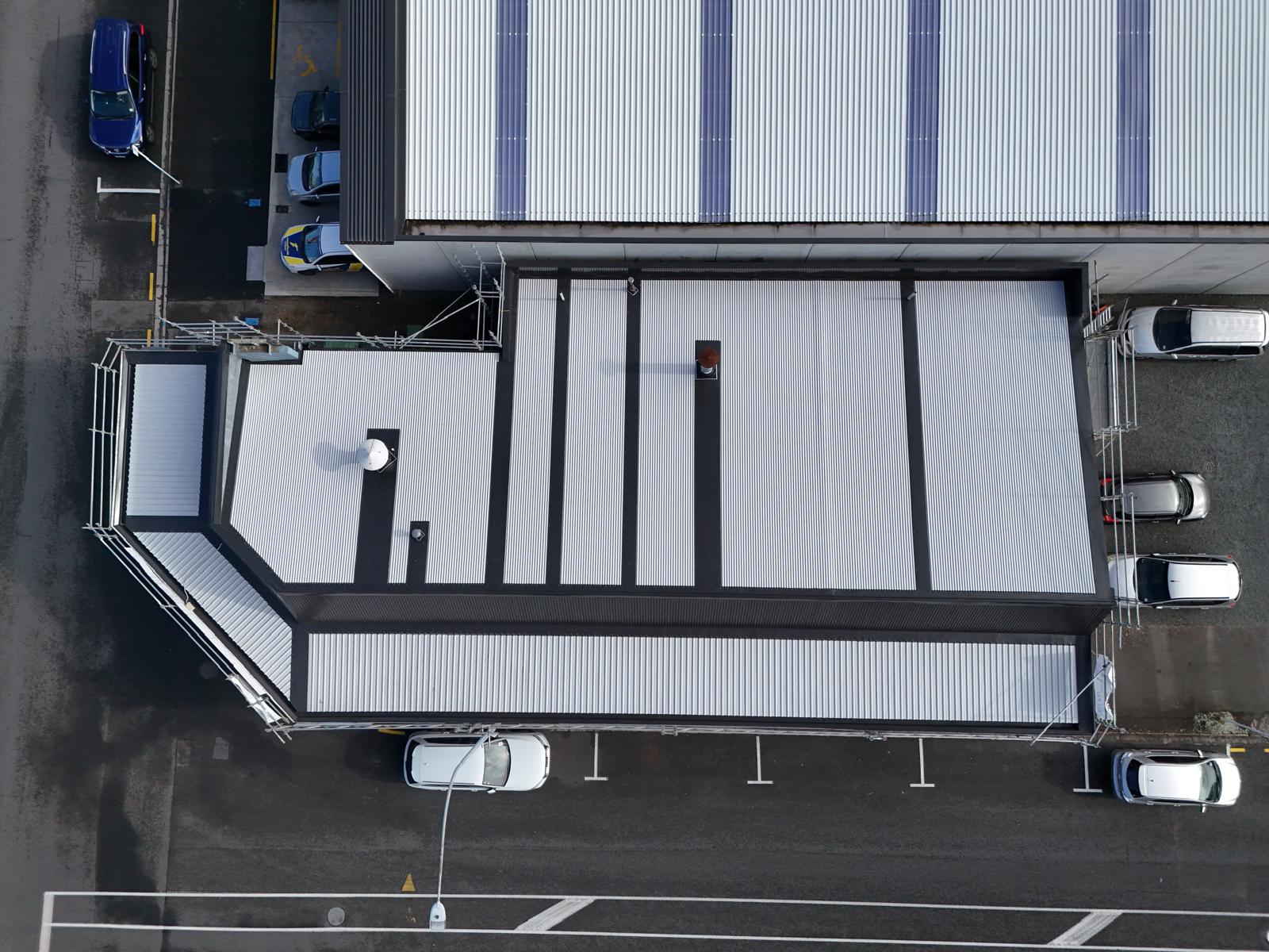 Top-down aerial of a completed long-run commercial roof and parapet cladding